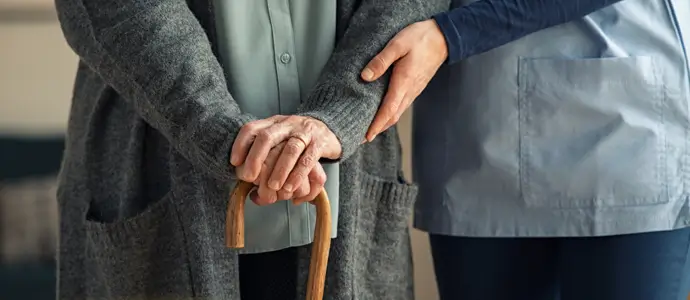 Aid helping elderly woman in nursing home