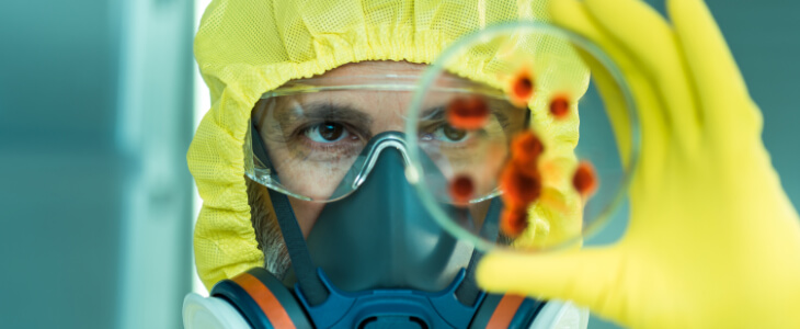 image of man in a hazard suit holding up a pietri dish