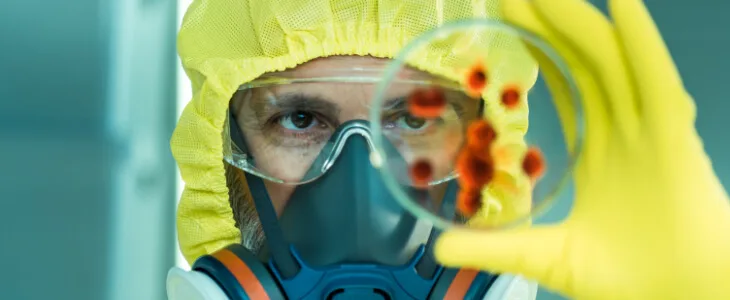image of man in a hazard suit holding up a pietri dish